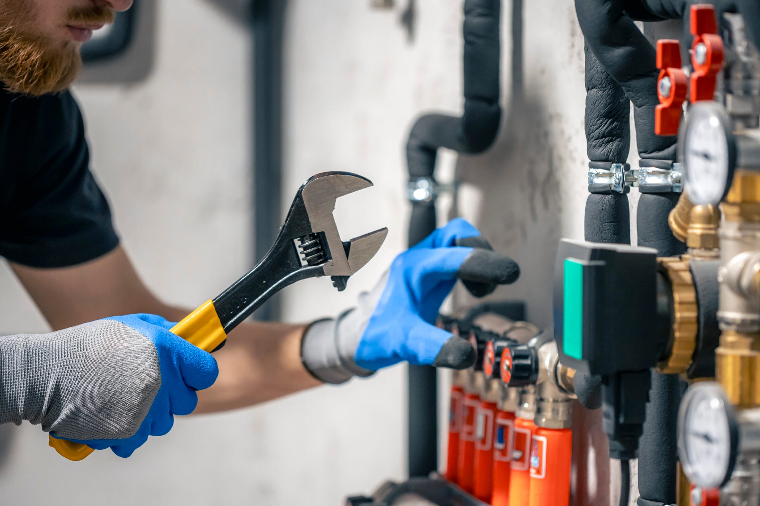 man installs heating system house checks pipes with wrench 1 scaled